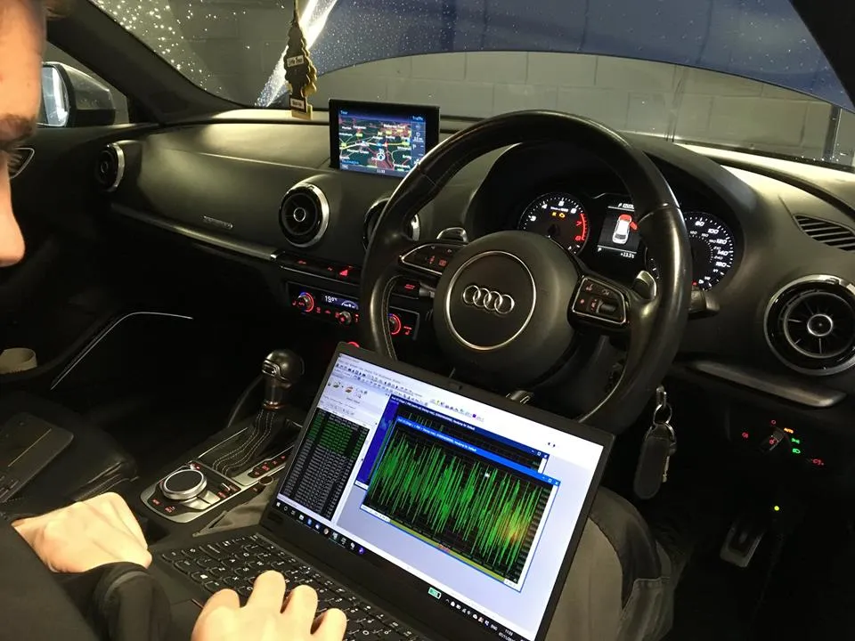 Technician remapping an Audi ECU with a laptop connected inside the car