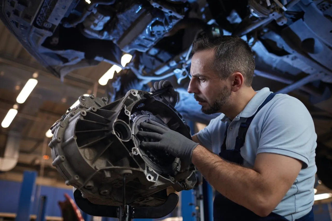 Mechanic inspecting a car gearbox in a workshop