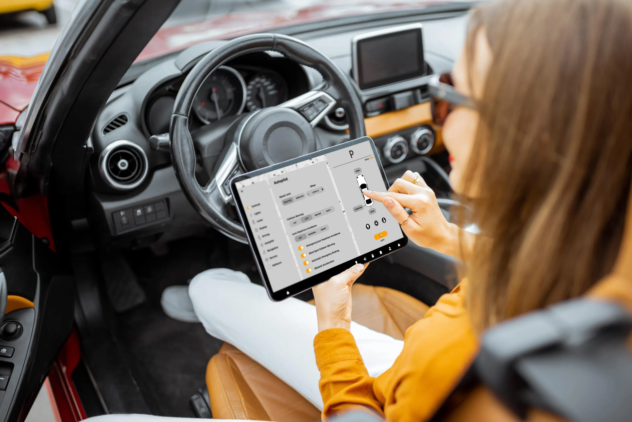 Driver using a tablet to check car settings inside the vehicle