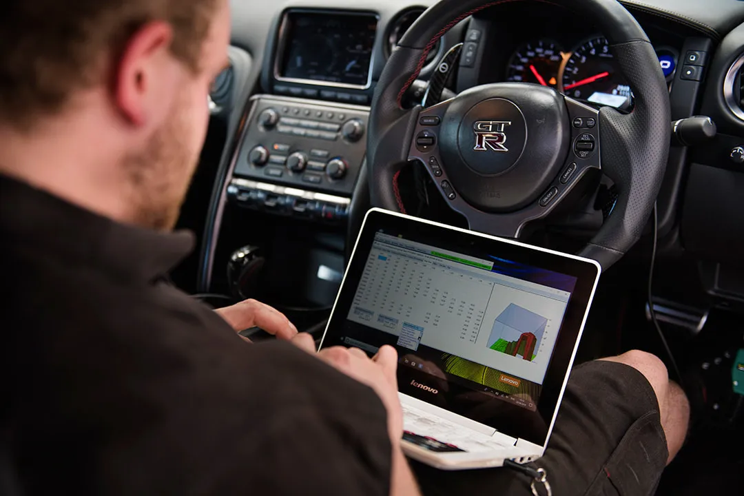Technician performing ECU remapping on a Nissan GT-R with a laptop