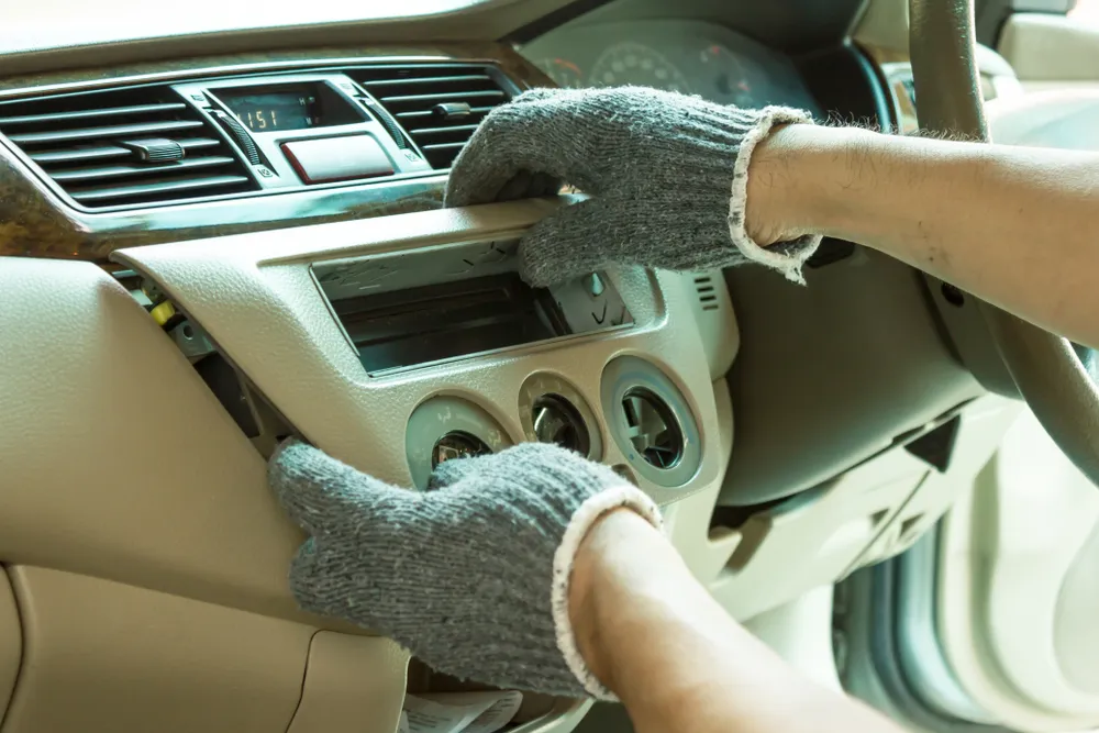 Technician removing a car dashboard panel for instrument cluster repair
